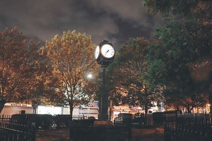 A Park Clock Lit up in  the Center of a Plaza