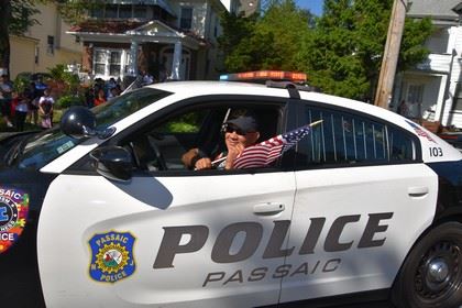 Passaic Police Officer Waving a Small American Flag out of His Cruiser Window